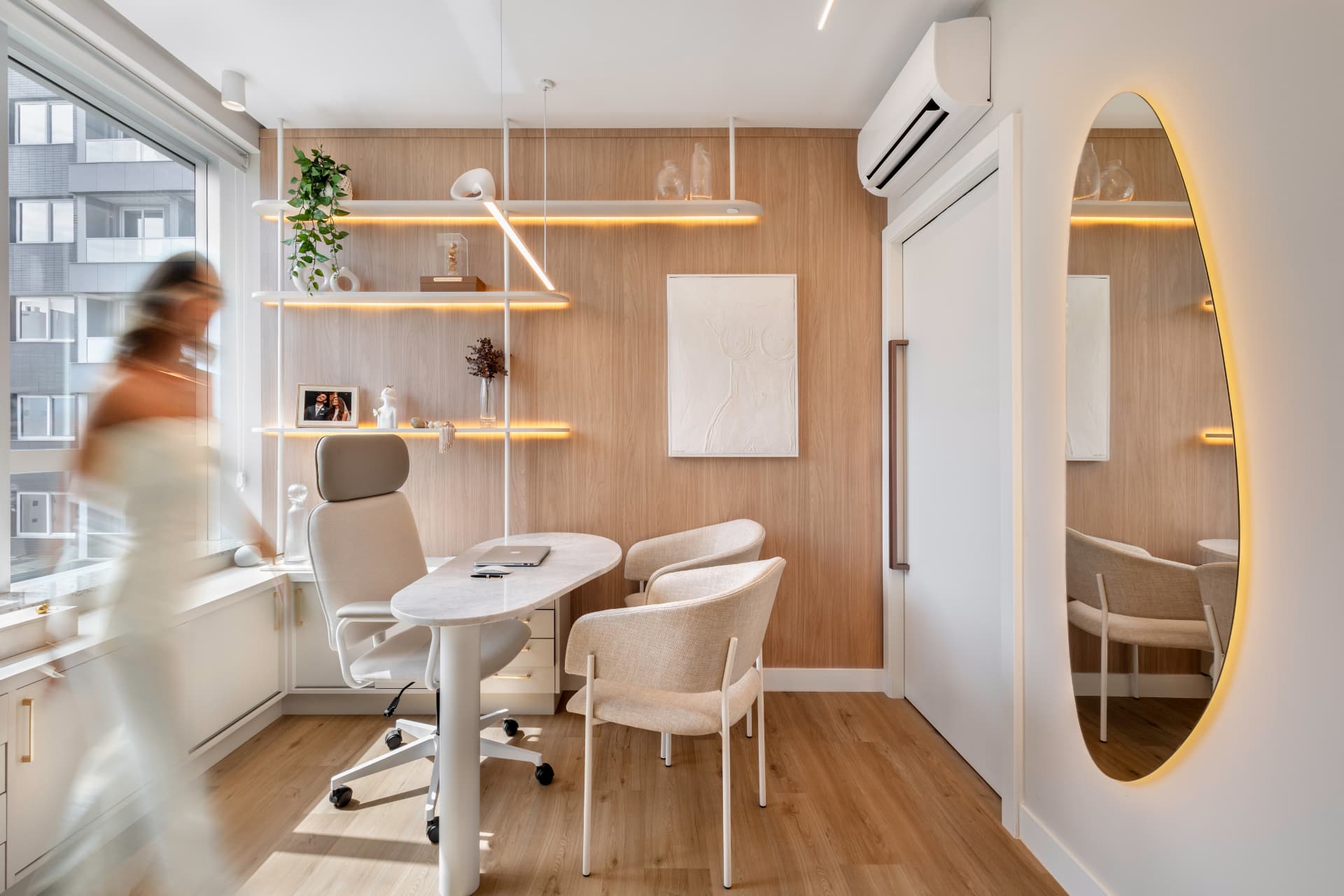 Consultório com prateleiras iluminadas, painel de madeira e espelho orgânico com LED